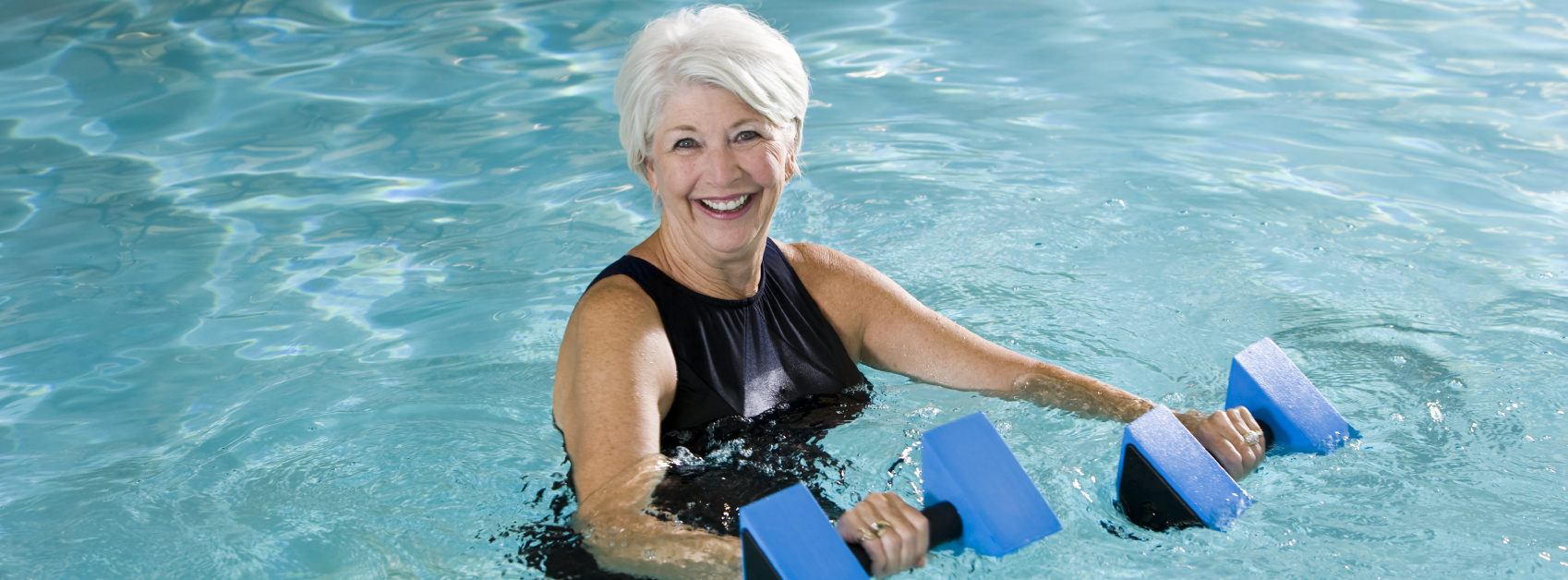 A senior lady is happily doing water exercise